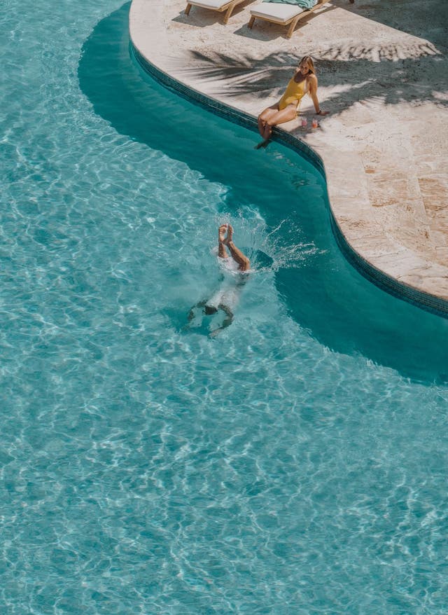 Entdecke die schönsten Stranddestinationen Mann springt in Pool Iberostar Beachfront Hotels