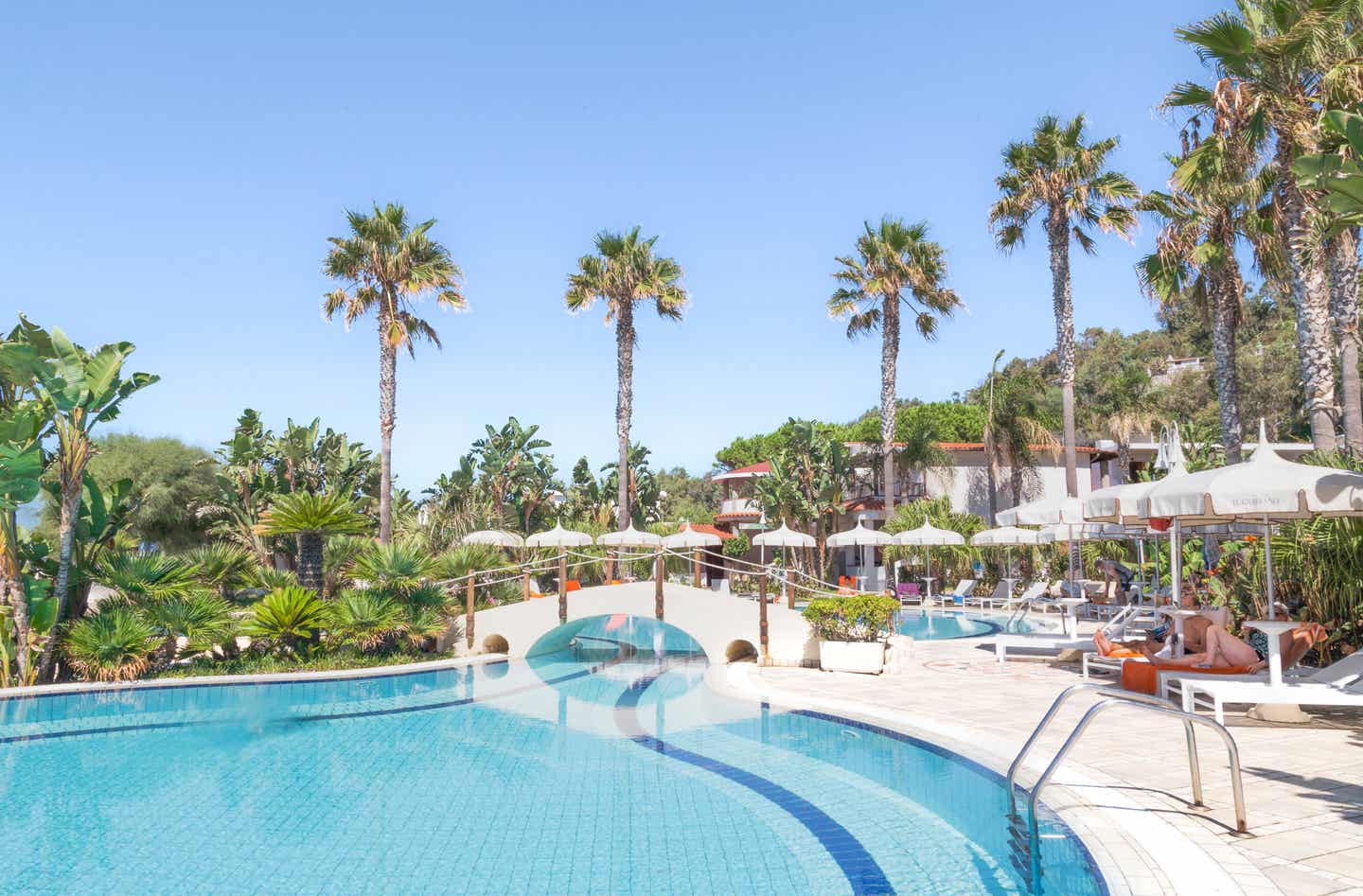 Blick auf den Pool des Villaggio Il Gabbiano Hotels mit Palmen im Hintergrund