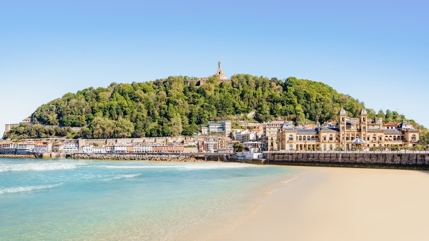 Blick auf San Sebastián: eine der schönsten Städte am Meer in Spanien. Blaues, flaches Wasser und lange Promenade.