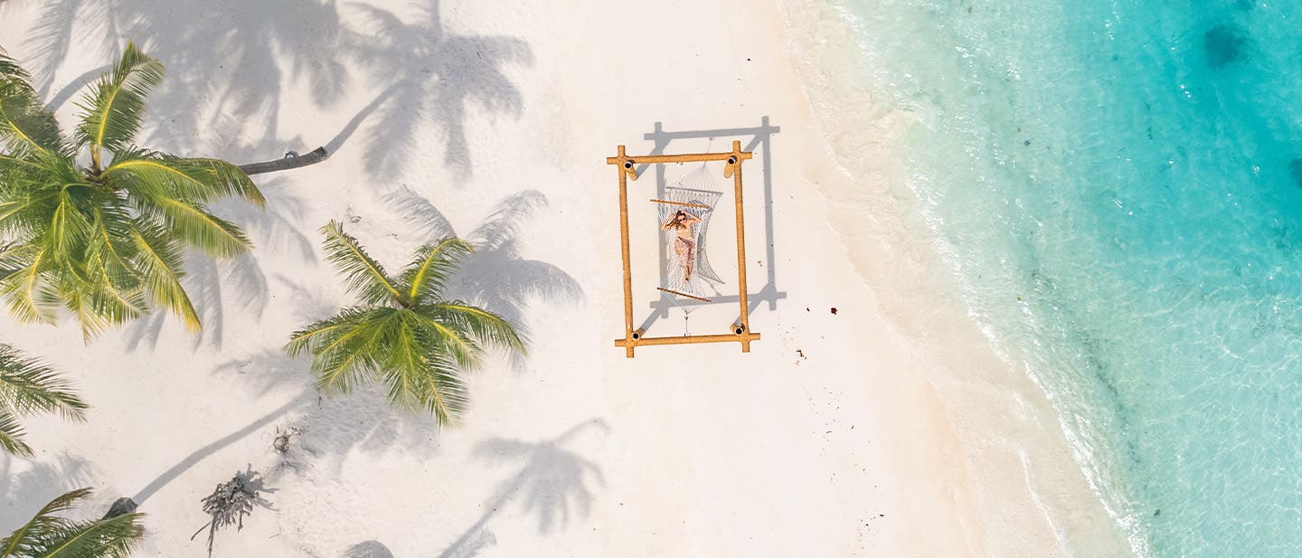 Eine Frau in einer Hängematte am Strand auf den Malediven