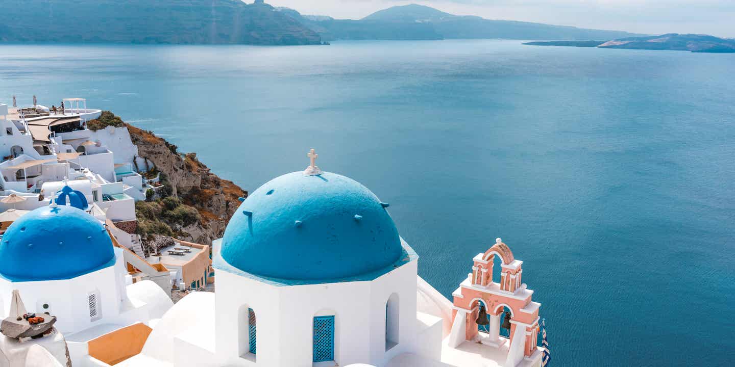 Oia mit weißen Häusern und blauen Kuppeln an der Caldera bei Sonnenuntergang – beliebter Instagram-Spots auf Santorini 
