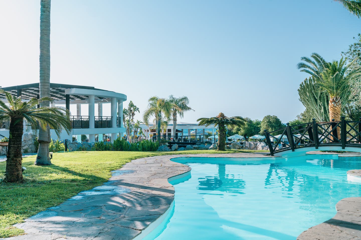 Pool des Calypso Beach mit Sonnenliegen und Palmen im Hintergrund