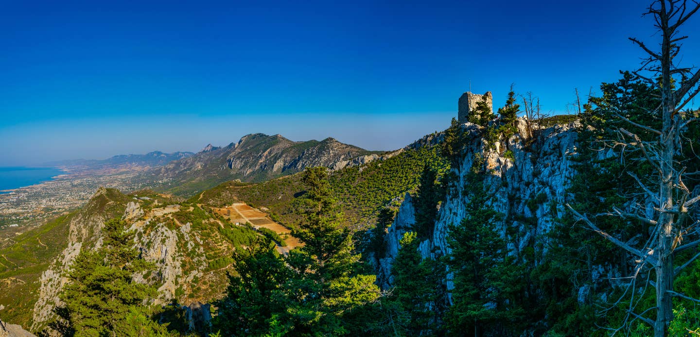 Rundreisen Zypern: Panoramabild Zyperns gebirgiger Landschaft mit dem Meer in Hintergrund und vorn der Burgruine St. Hilarion Rundreisen Zypern: Panoramabild Zyperns gebirgiger Landschaft mit dem Meer in Hintergrund und vorn der Burgruine St. Hilarion