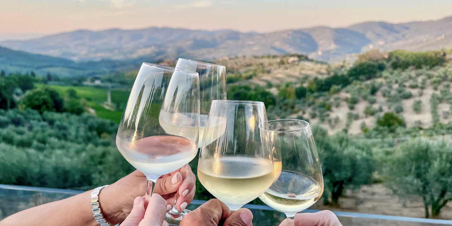 Prostende Weißweingläser vor der kulisse der Toskana