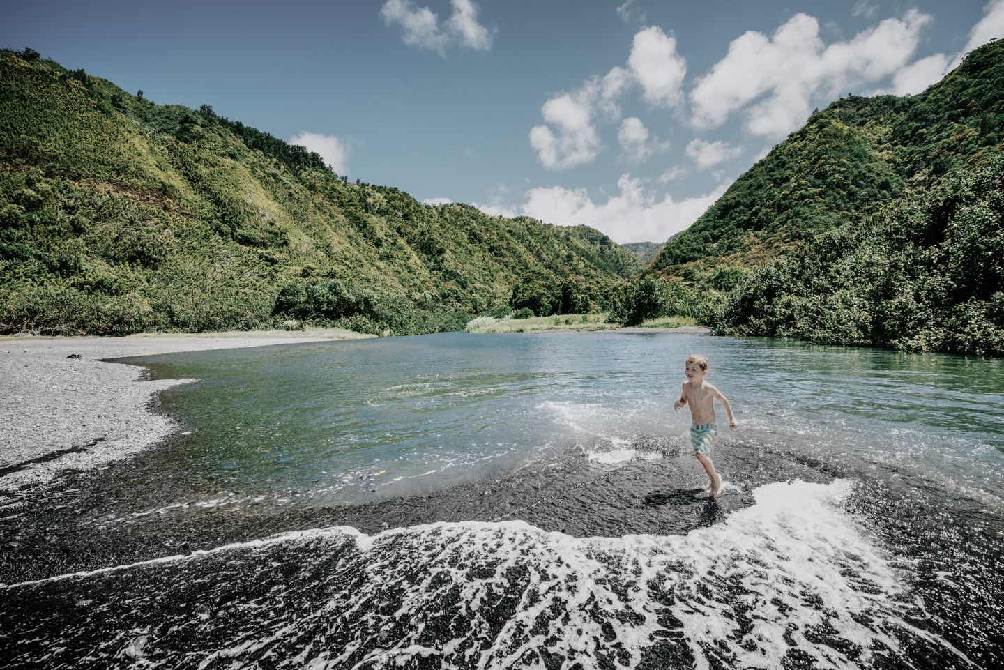 Maui Urlaub mit DERTOUR. Junge spielt in einem Fluss in Hana, Maui