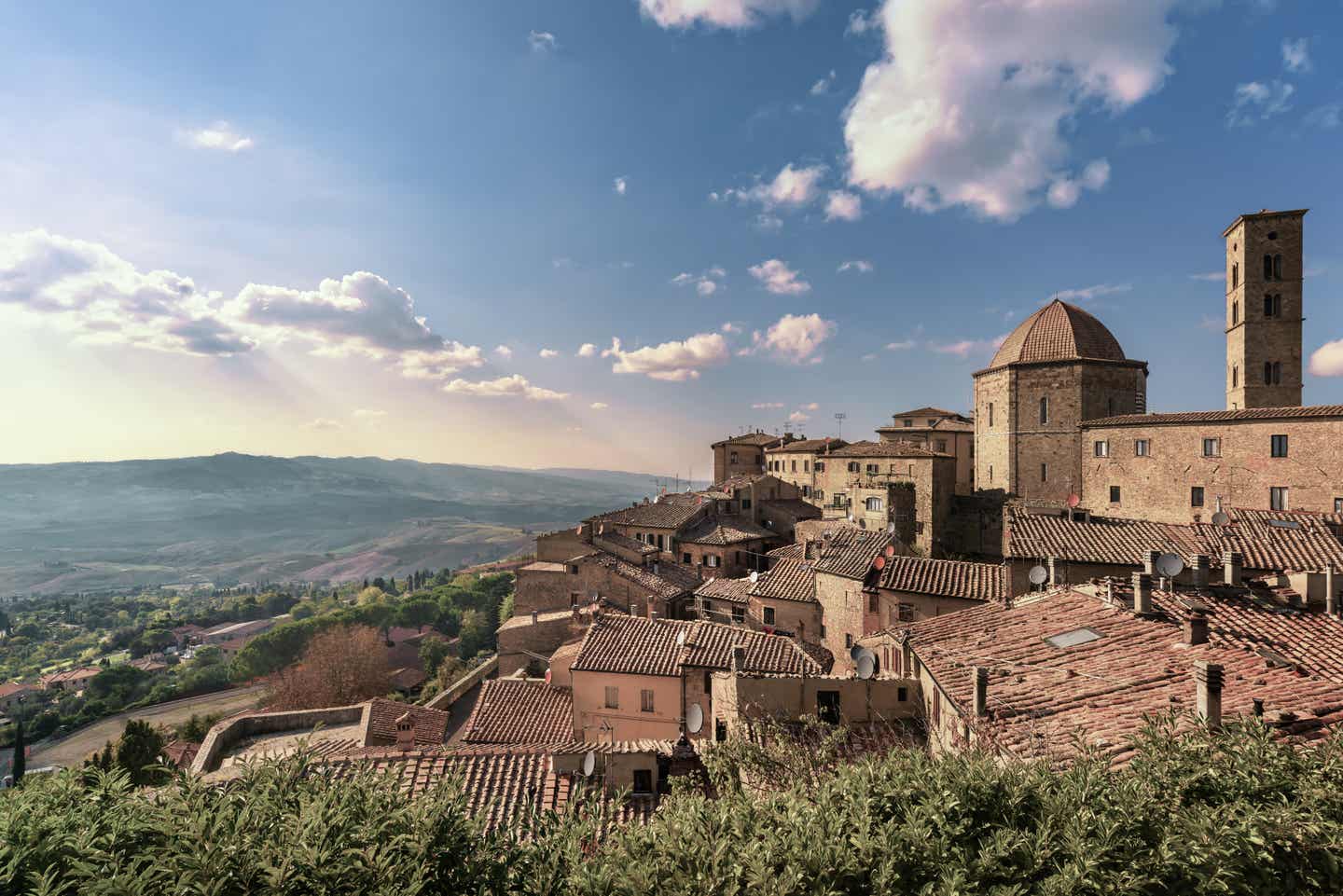 Toskana Urlaub mit DERTOUR. Blick auf das Städtchen Volterra mit der grünen toskanischen Landschaft im Hintergrund