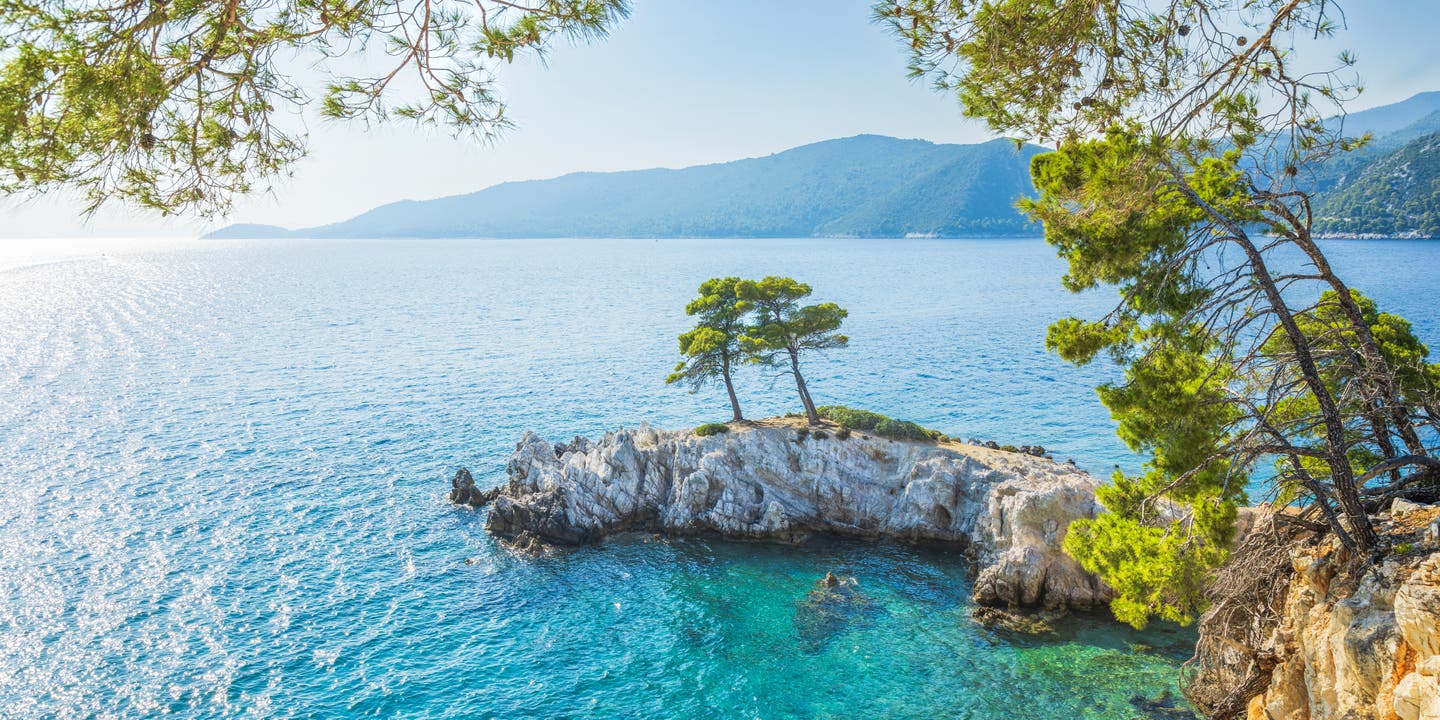 Insel mit zwei Bäumen im türkisblauen Meer bei Griechenland
