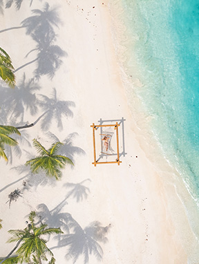 Eine Frau in einer Hängematte am Strand auf den Malediven