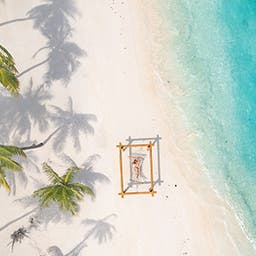Eine Frau in einer Hängematte am Strand auf den Malediven