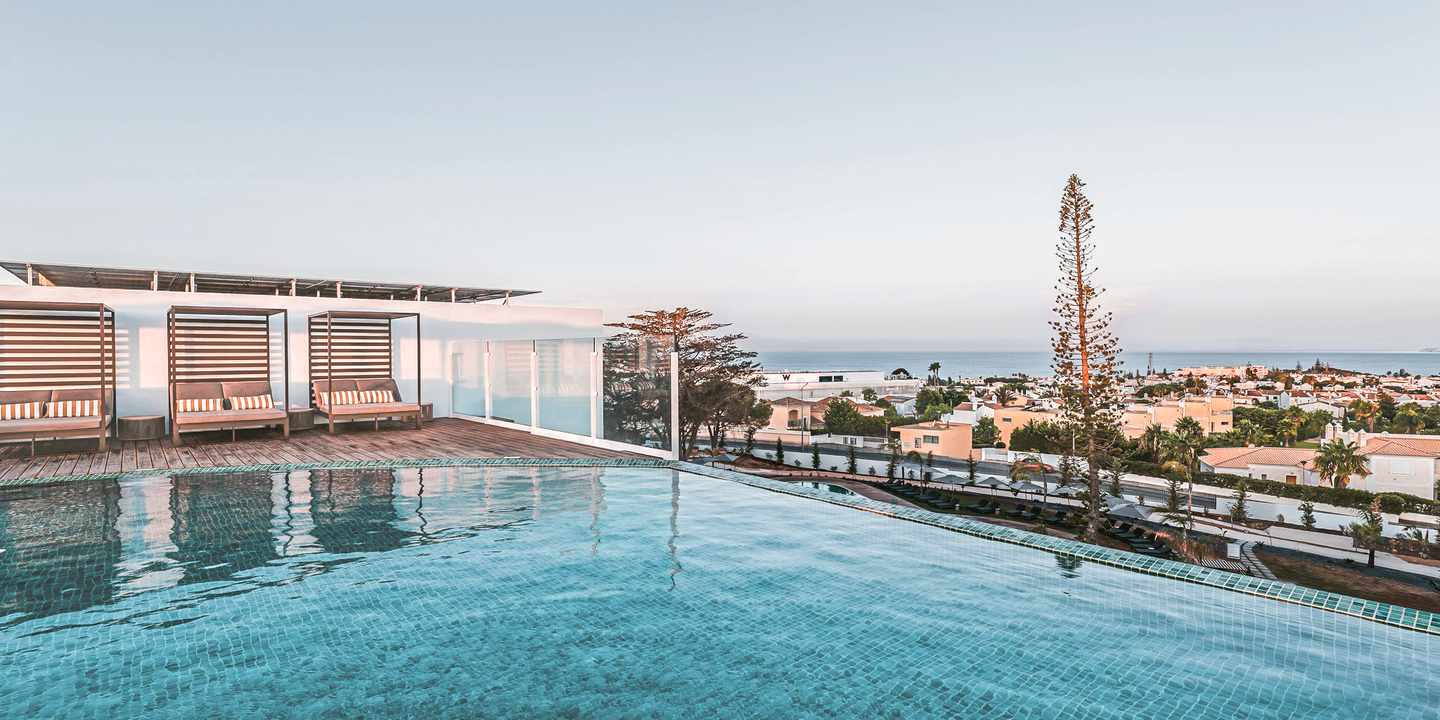 Panoramaaussicht vom Poolbereich des ananea Castelo Suites Algarve über die Dächer von Sesmaria, im Hintergrund das Meer