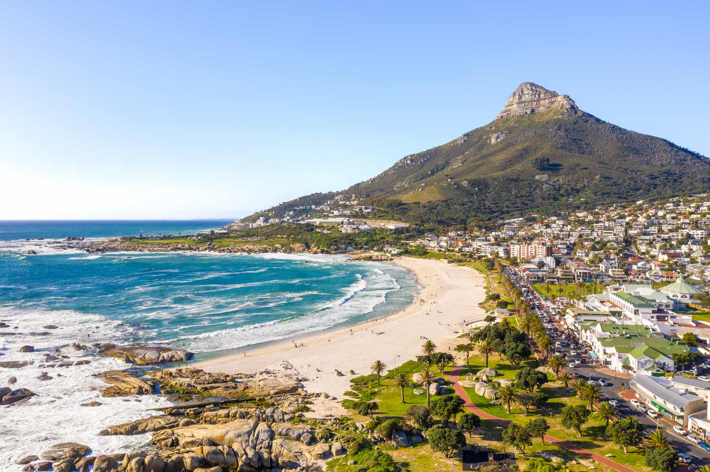Luftaufnahme vom Strand in Camps Bay, Kapstadt – weißer Sand, Atlantikbrandung und der markante Lion’s Head im Hintergrund.
