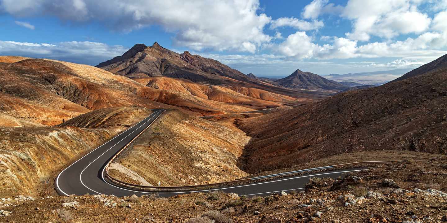 Kurvenreiche Straße am Mirador de Sicasumbre mit Blick auf Montaña Cardón und trockene Berglandschaft auf Fuerteventura