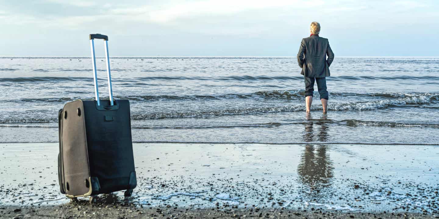 Mann steht am Meer mit einem Anzug an