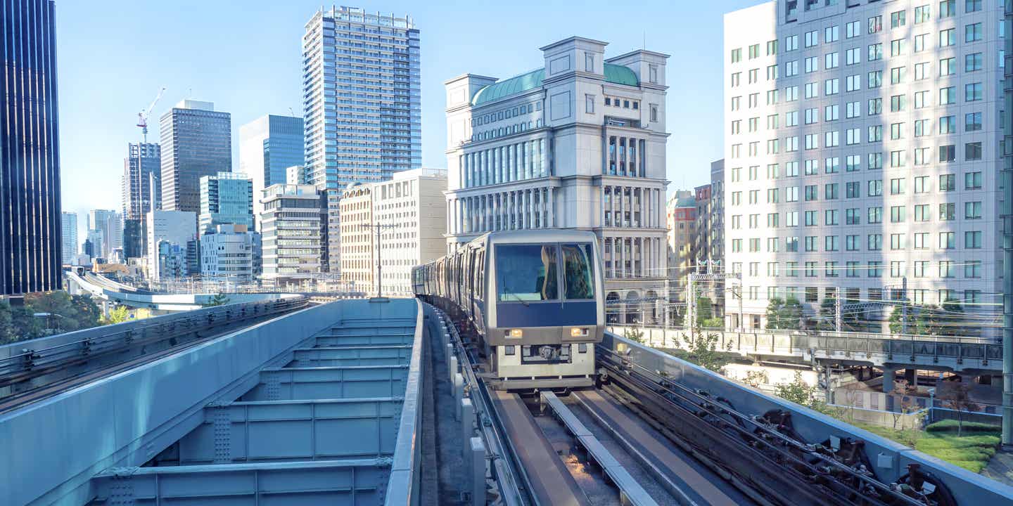 Zug der Tokio Metro fährt über eine Brücke vor Hochhäusern bei Tageslicht