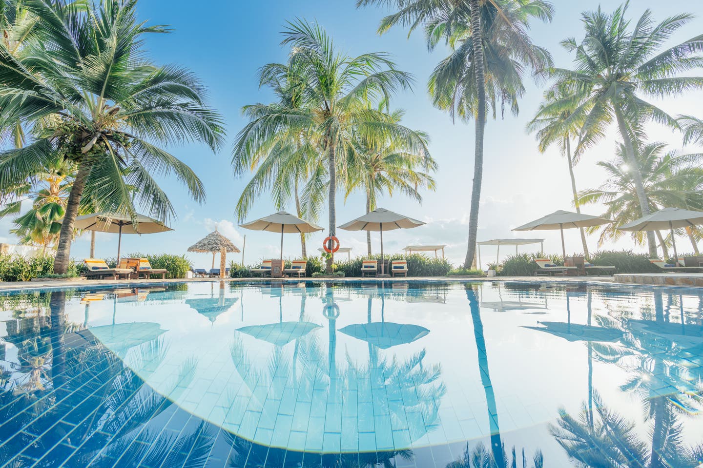 Pool des Resorts mit Liegestühlen und Palmen