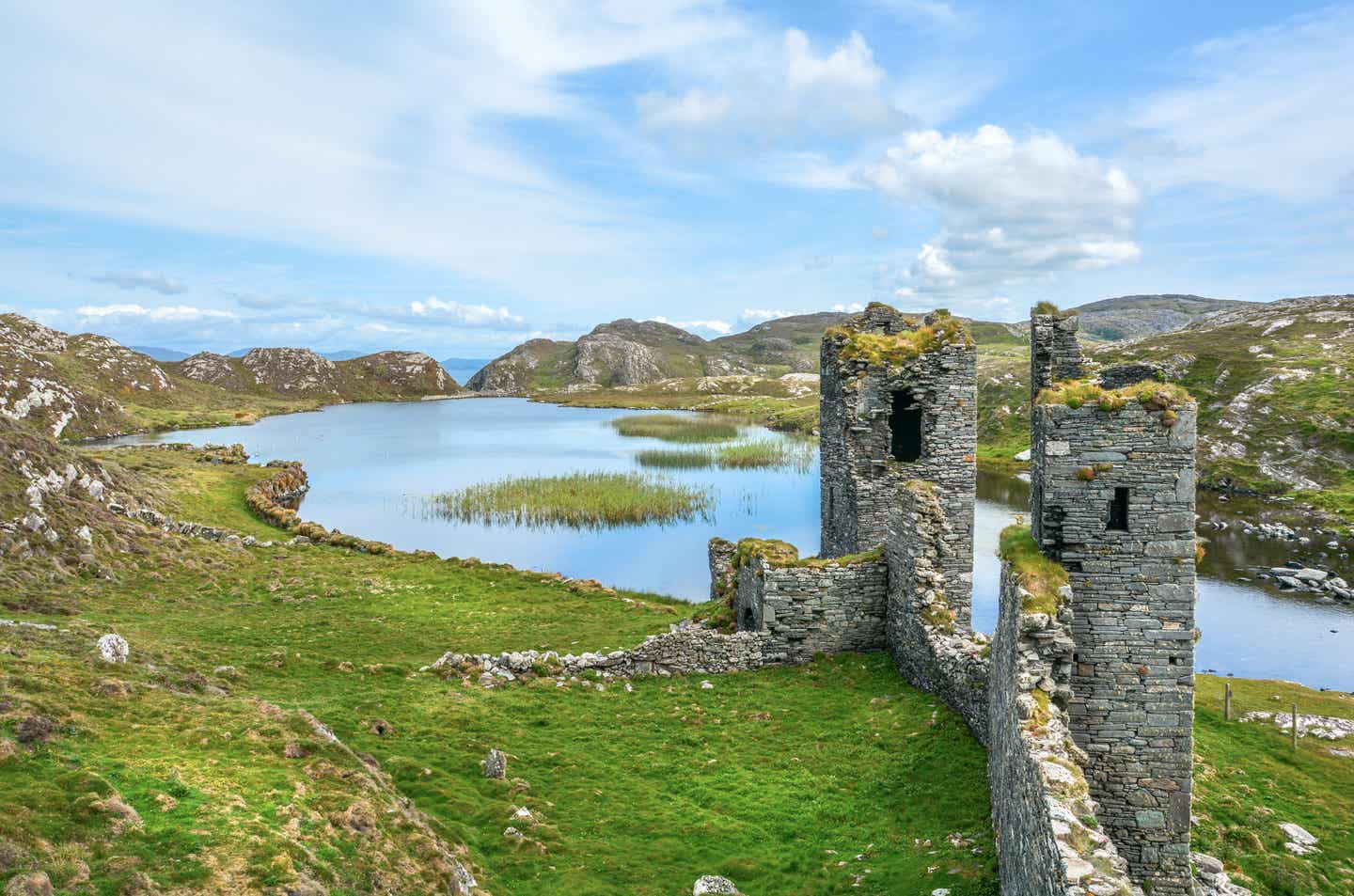Eindrucksvolle Ruinen in grüner Landschaft vor einem See