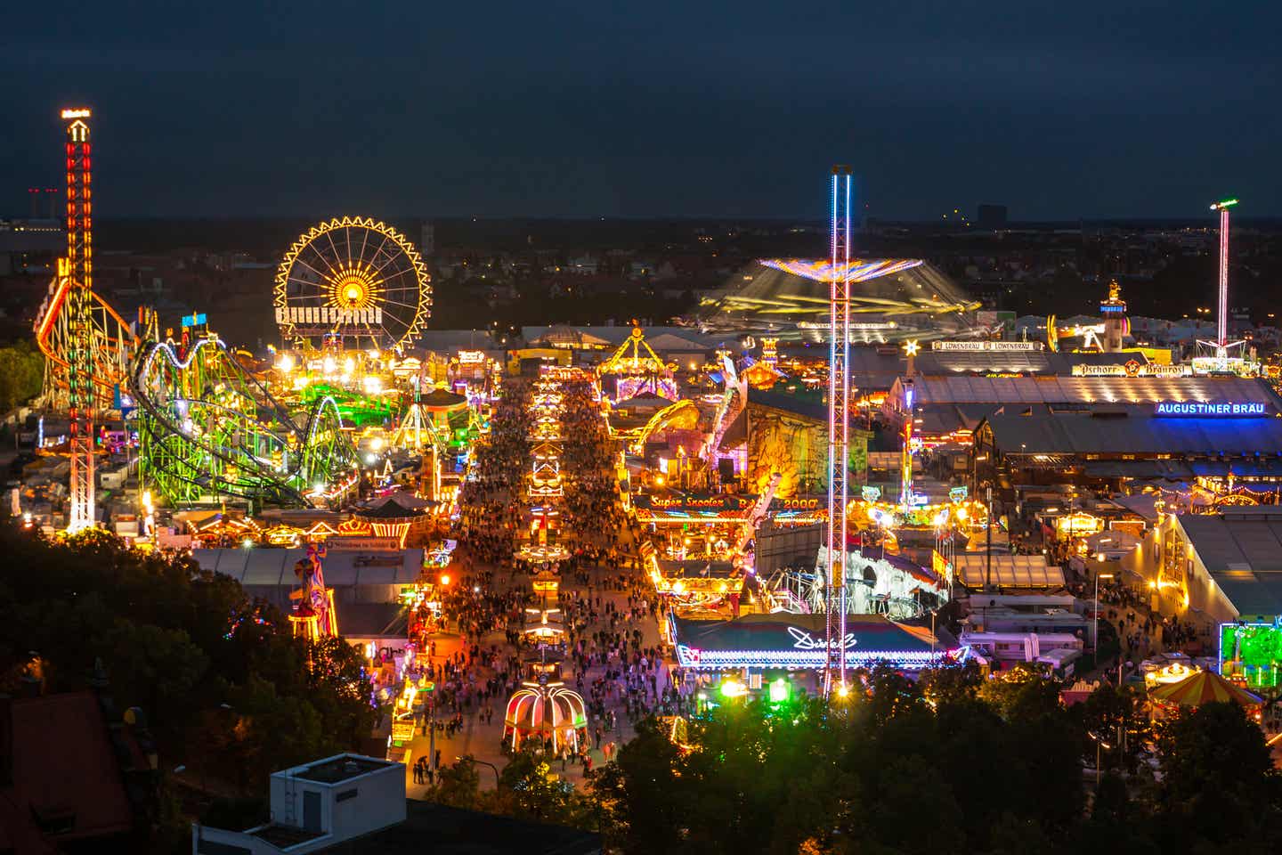 München bei Nacht: beleuchtetes Oktoberfest, bunte Farben, Riesenrad und Fahrgeschäfte