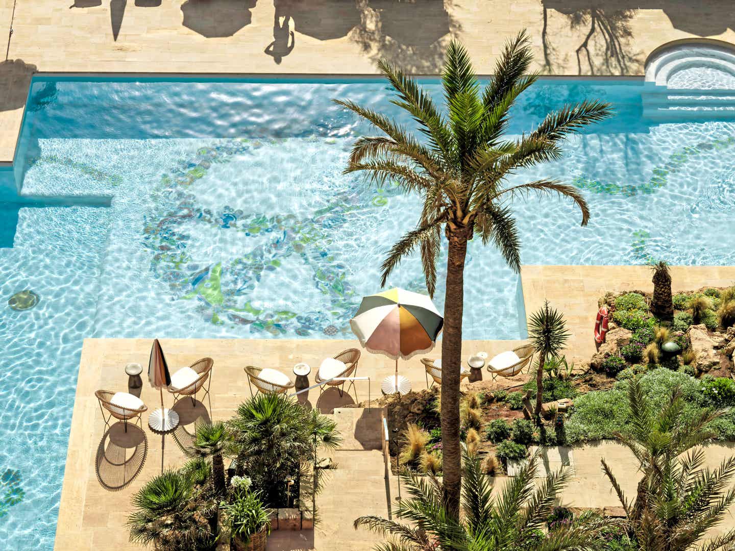 Vogelperspektive auf einen Pool mit Peace Zeichen, Palmen und Stühlen
