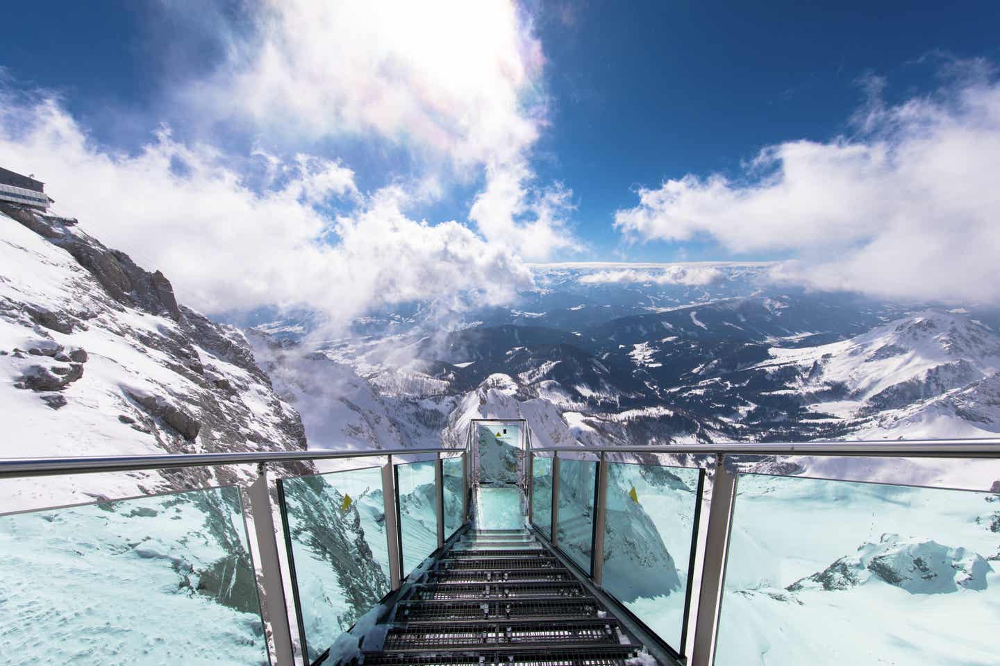 Gläserne Aussichtsplattform vor verschneiten Bergen in Ski amadé