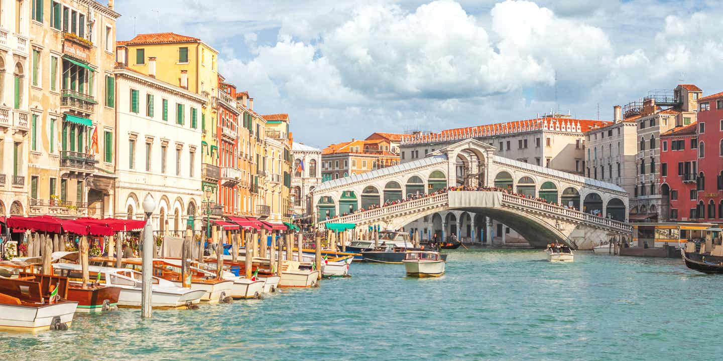 Blick auf die Rialto-Brücke und den Canal Grande in Venedig bei Nachmittagssonne mit Gondeln im Vordergrund
