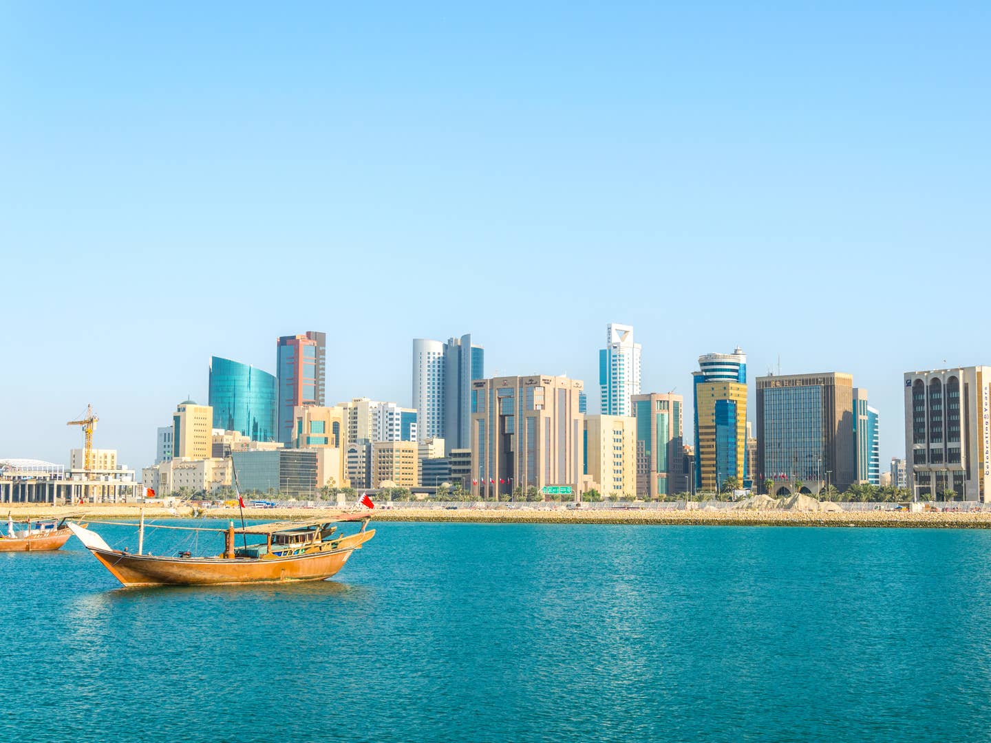 Skyline von Bahrain mit traditionellem Dhow-Boot aus Holz im Vordergrund