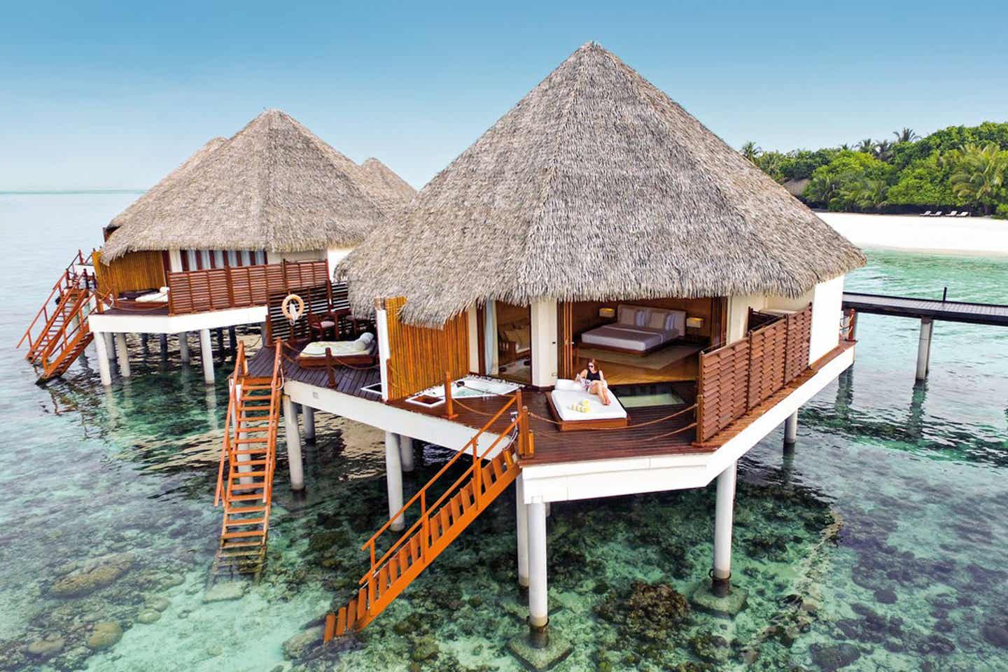 Wasserbungalows mit Treppen, die direkt ins Meer führen und einer Insel im Hintergrund