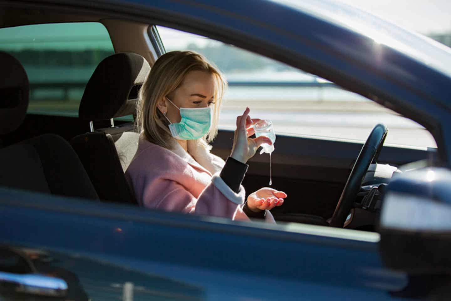 Hygienetipps für den Urlaub während Corona: Frau sitzt im Auto mit Maske
