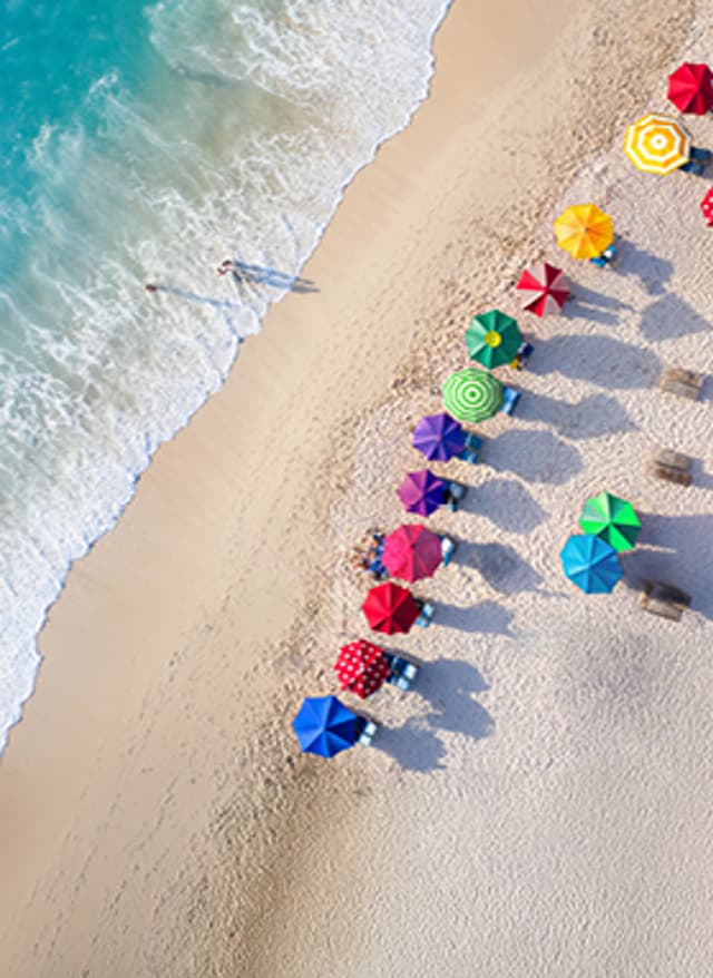 Jetzt entdecken Bunte Sonnenschirme an einem Strand