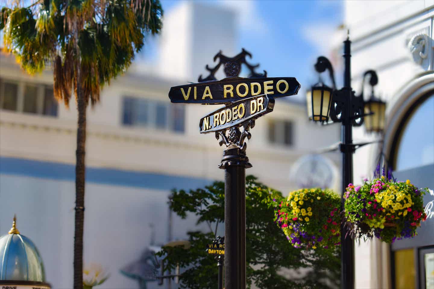 Der Rodeo Drive in Los Angeles im Sonnenlicht mit Blumen und Palmen.