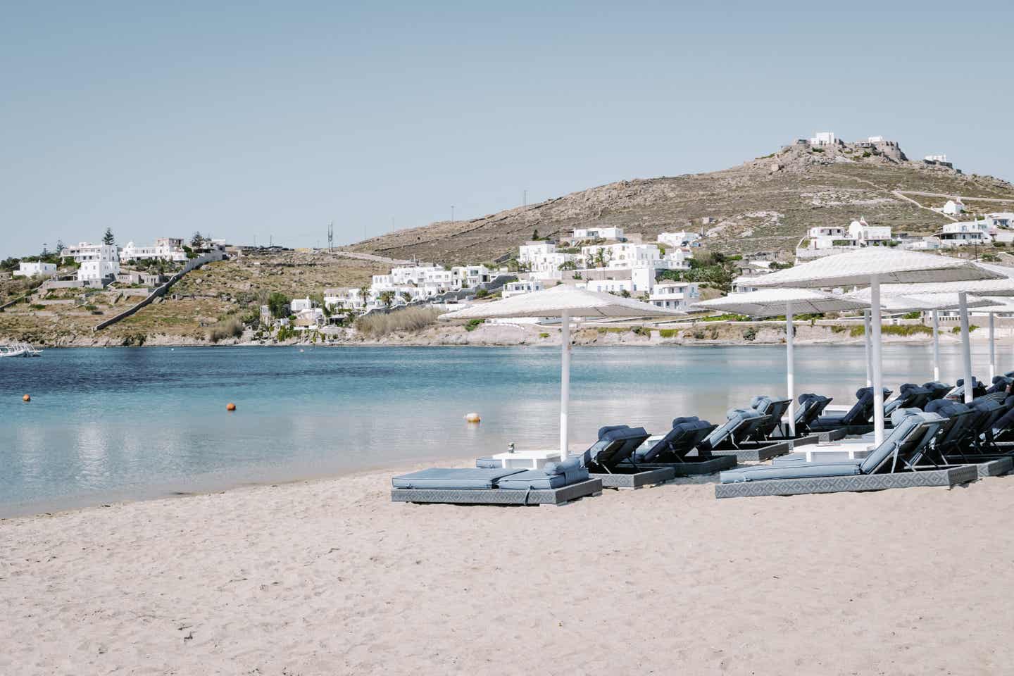 Mykonos Strände: Sonnenliegen und Hügellandschaft am Ornos Beach