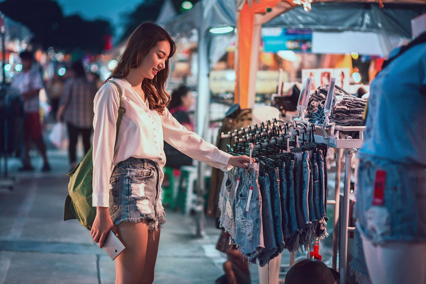 Eine Frau schaut sich Abends auf einem Flohmarkt um