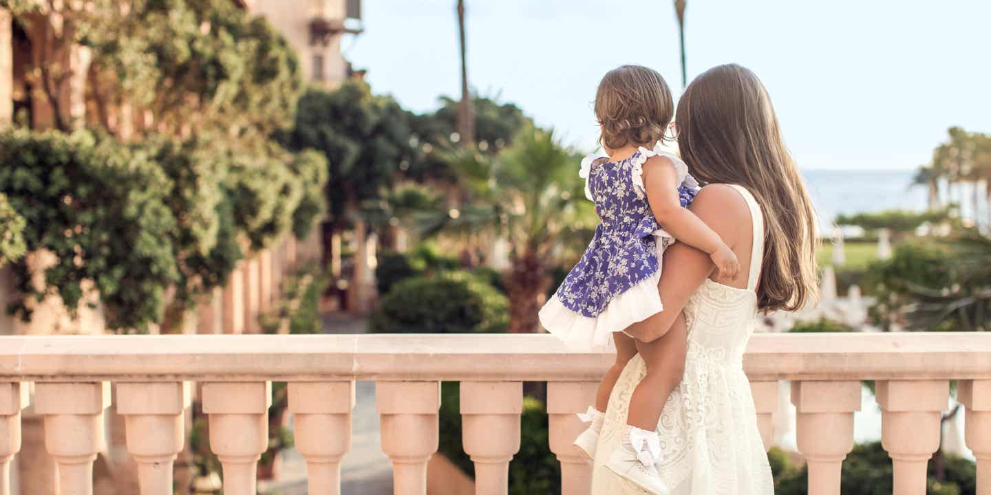 Mutter und Tochter stehen an einer Balustrade mit dem Rücken zum Betrachter