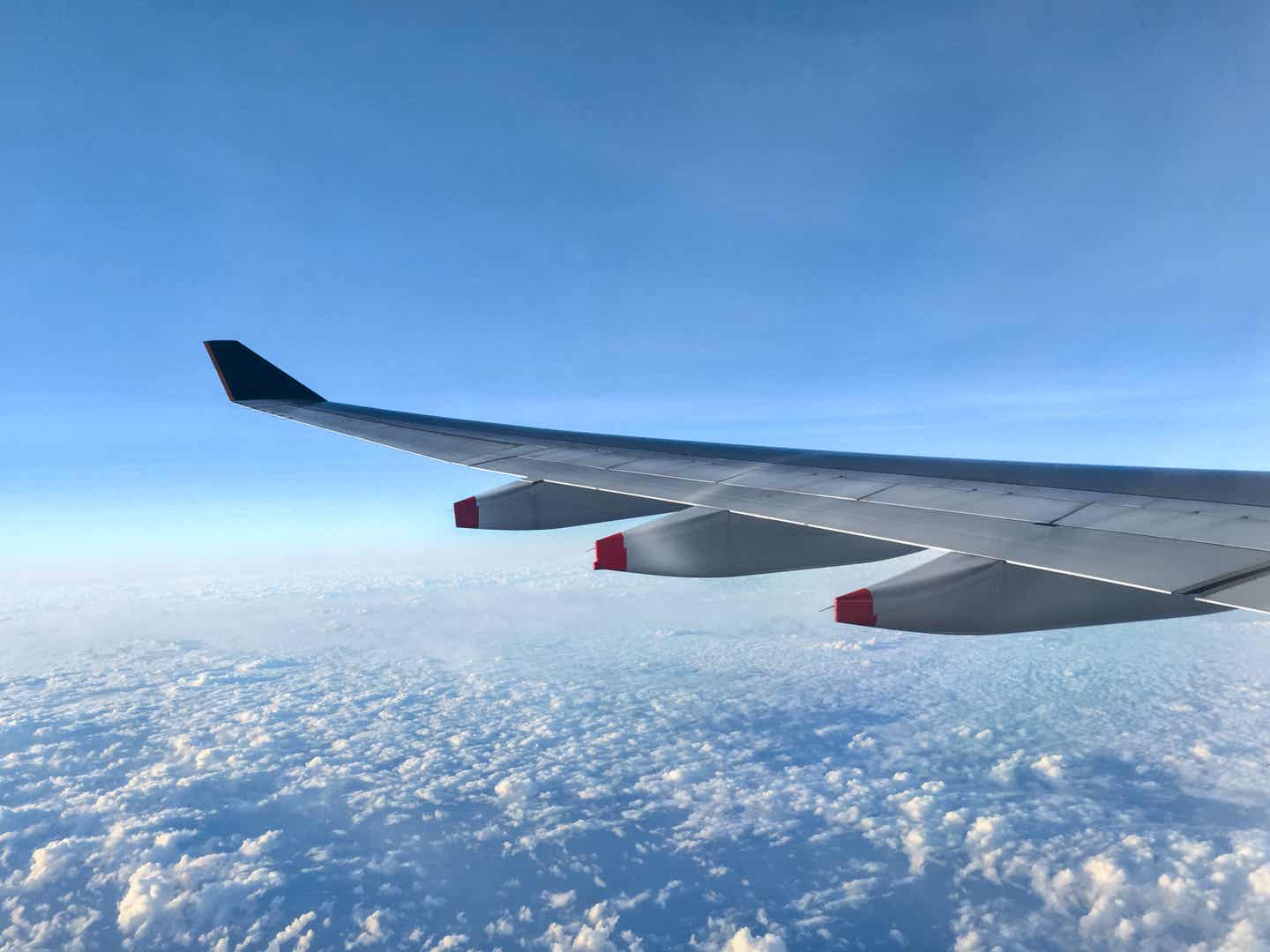 Blick auf die Tragfläche eines Flugzeugs, das hoch über den Wolken fliegt