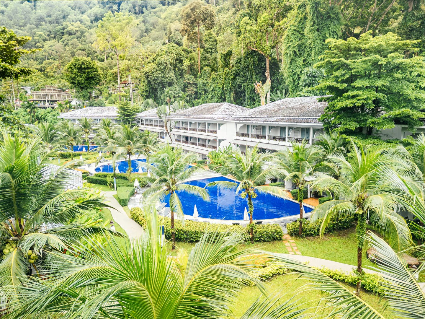 Luftbild der Hotelanlage mit Unterkünften und Pools umgeben von tropischem Wald
