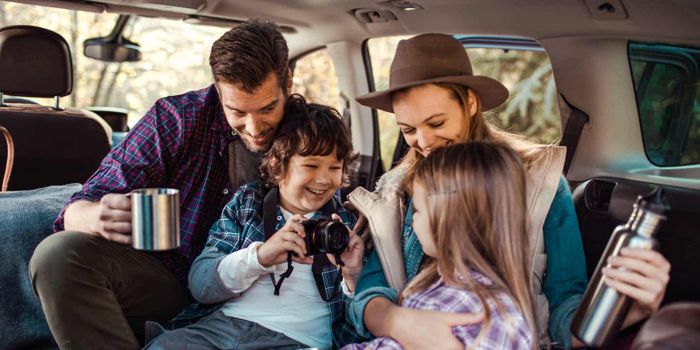 Eine Familie mit zwei Kindern sitzt im ausgebauten Kofferraum eines Autos