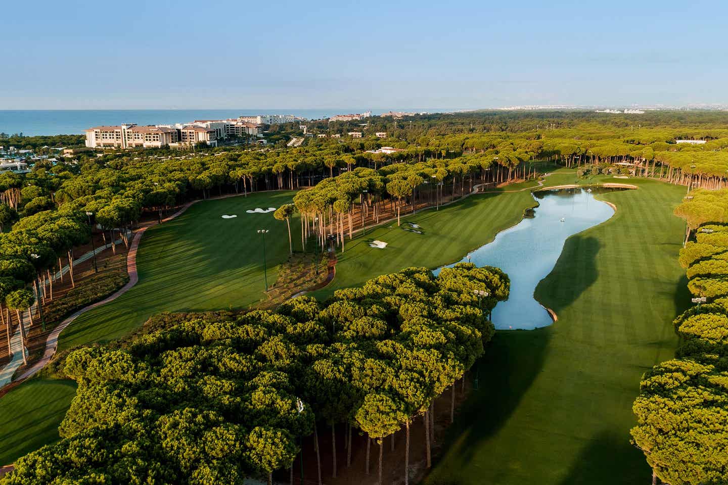 Blick auf den Carya Golf Club mit Wäldchen und See in der Mitte, Meer im Hintergrund