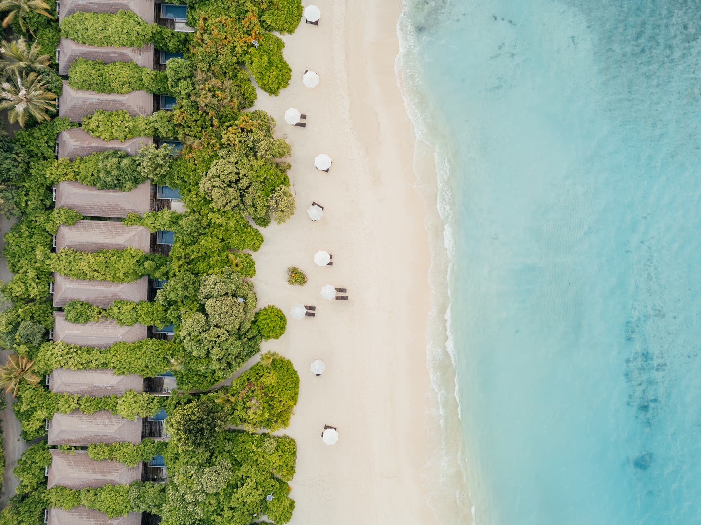 Topshot einer Drohne auf eine Reihe von Strandvillen mit Pool