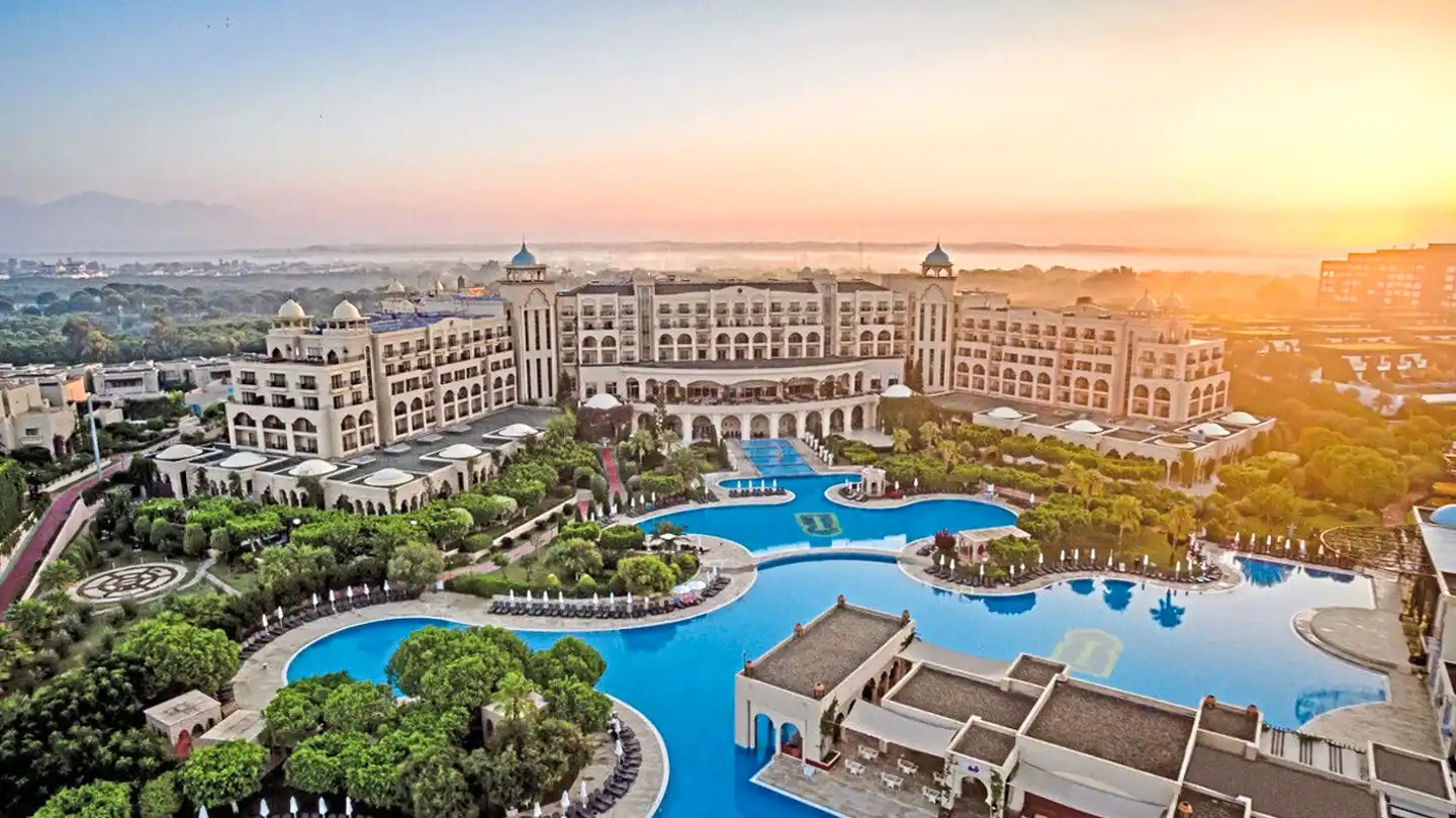 Spice Hotel & Spa aus der Vogelperspektive bei tiefestehender Sonne: monumentales Gebäude hinter großer Poollandschaft