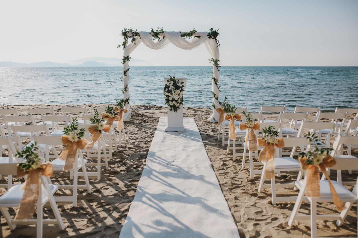 Geschmückter Bogen und dekorierte Sitzplätze für eine Hochzeit am Strand