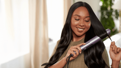 Femeie care își coafează părul cu ondulatorul