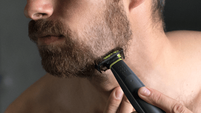 A close-up image of a man shaving his beard with a Philips OneBlade into a fade beard style.