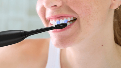 A close-up of a woman brushing her teeth with a Philips electric toothbrush