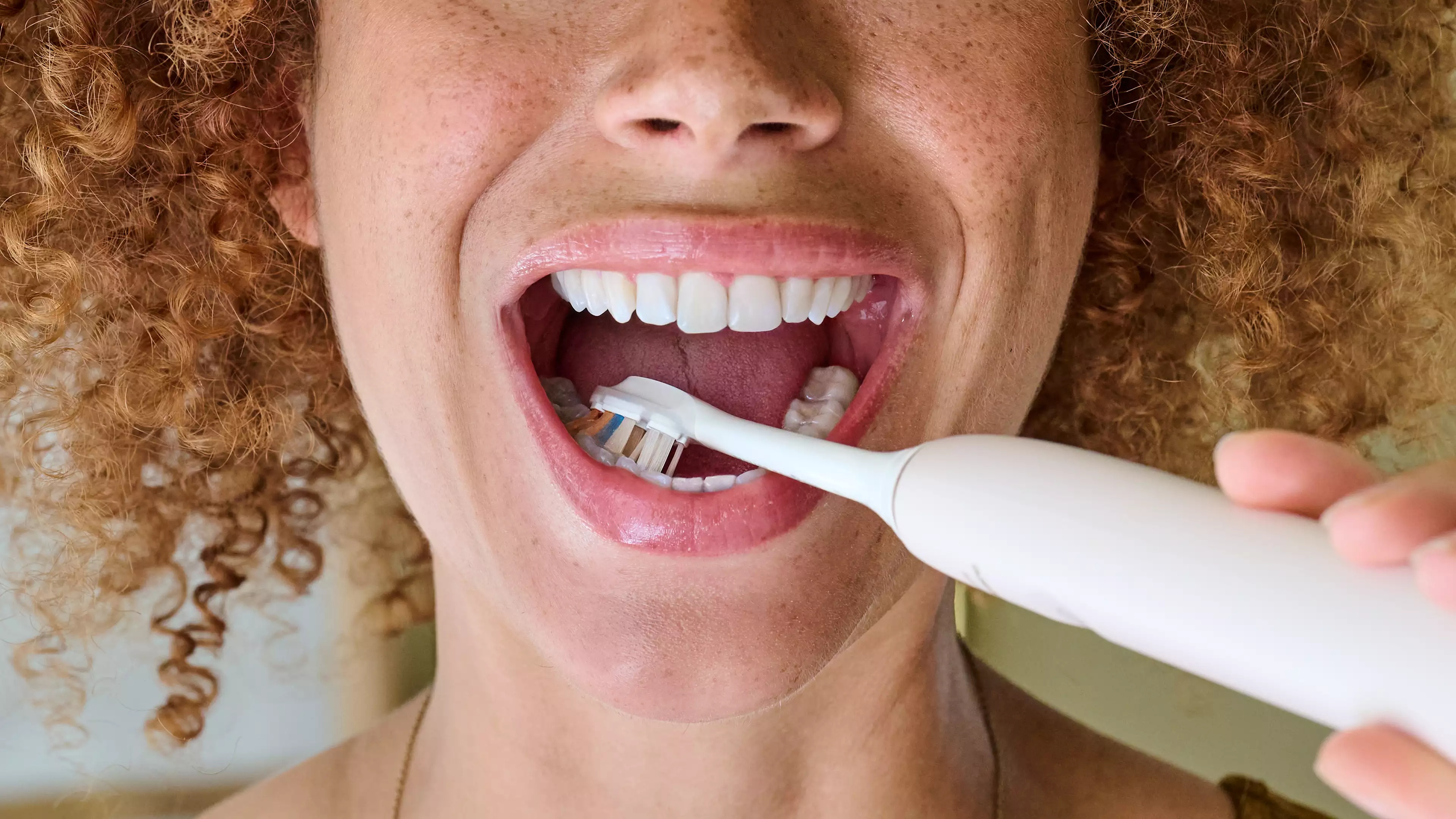Kobieta myjąca zęby szczoteczką soniczną Philips Sonicare
