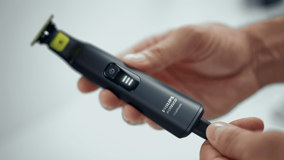 Product close-up image of a Philips OneBlade being attached to its charging cable.
