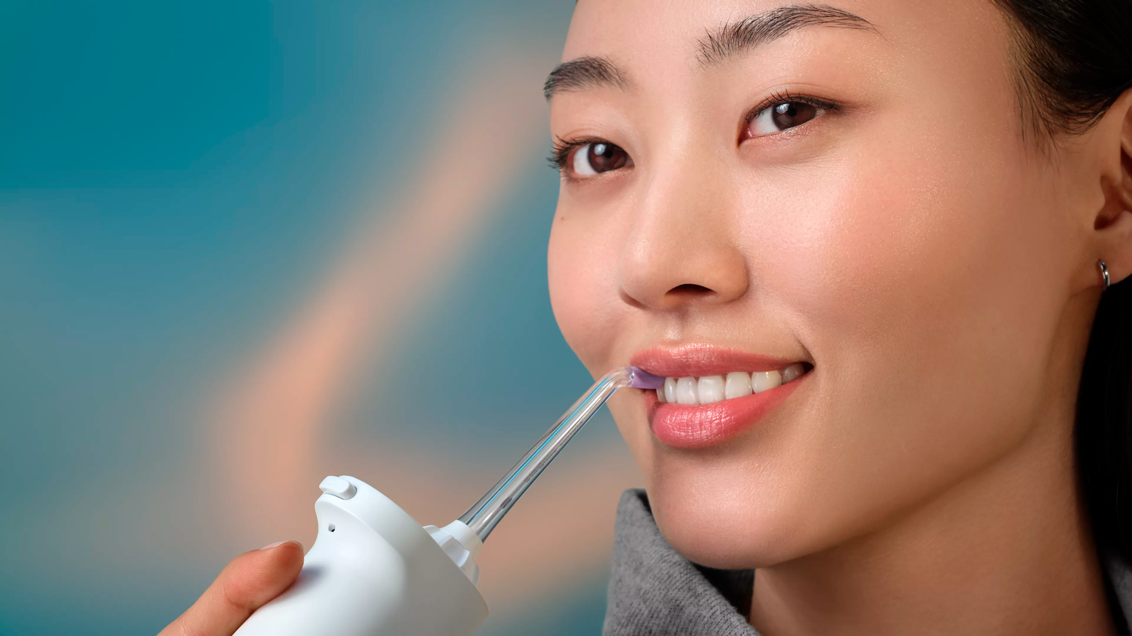 A woman using a Philips Sonicare Cordless Power Flosser.