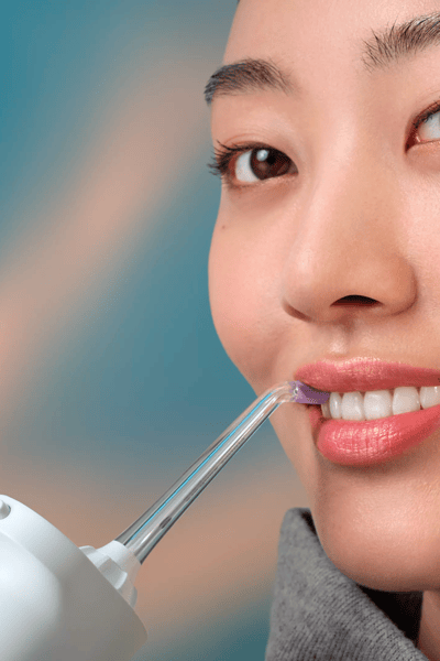 Une femme utilisant un Philips Sonicare Power Flosser sans fil.