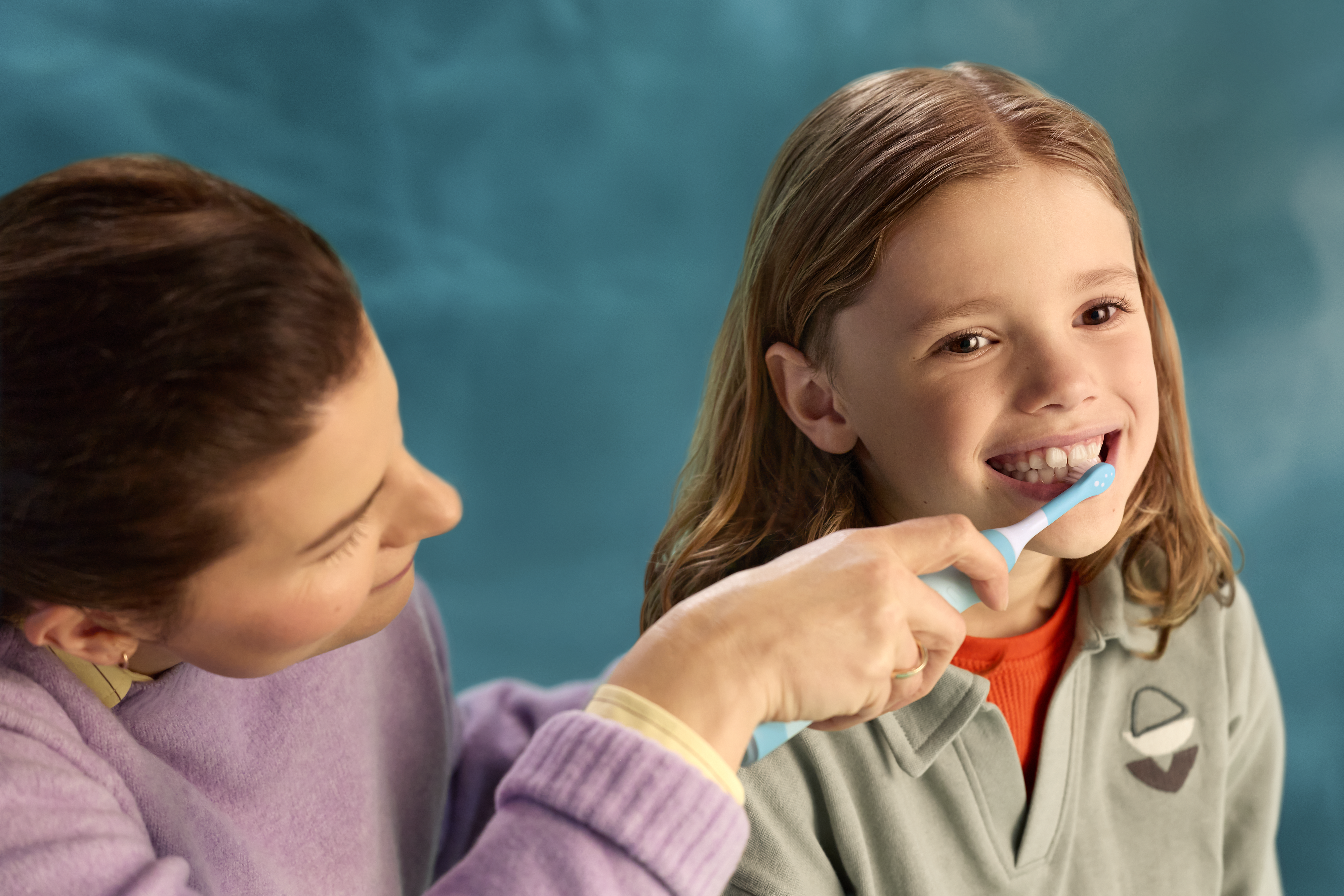 Дитина чистить зуби під керівництвом батьків