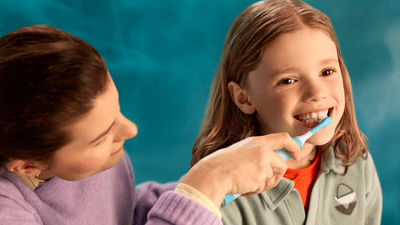 Дитина чистить зуби під керівництвом батьків