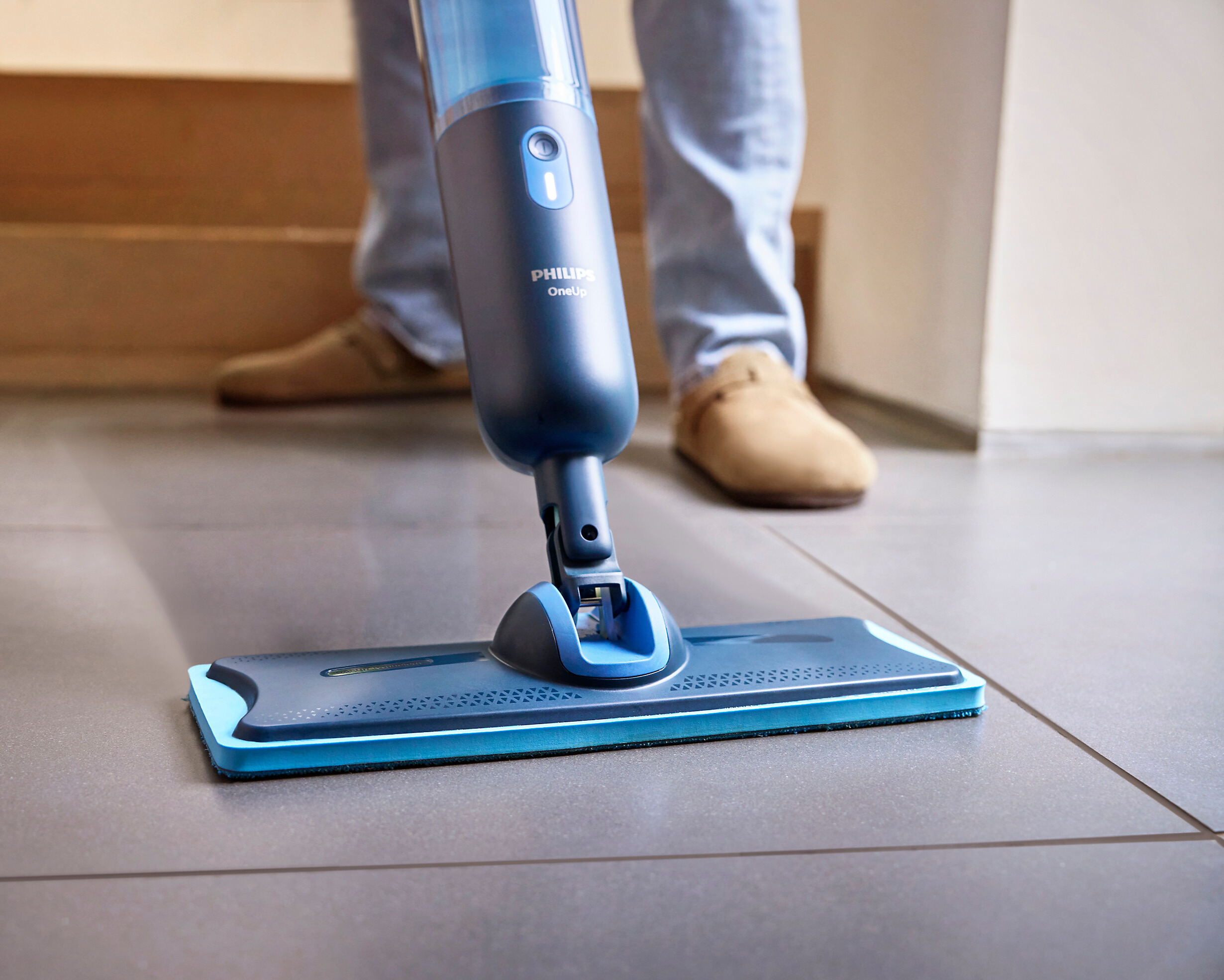 Близък план на син моп, който почиства под със сиви плочки