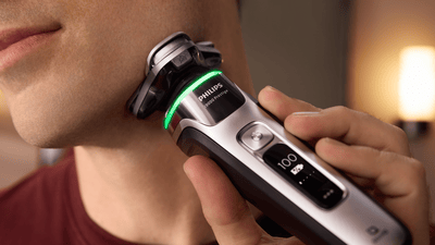A close-up image of a man shaving his beard with a Philips silver shaver.